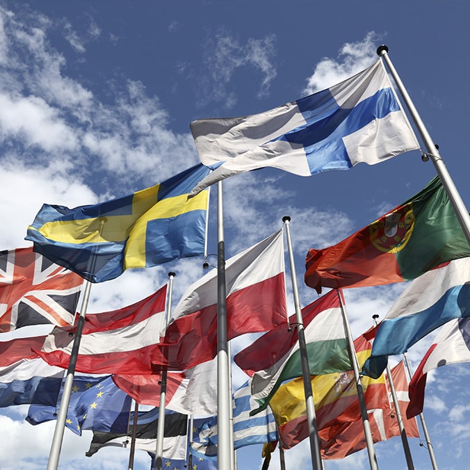 Several flags of different countries flying in the wind.